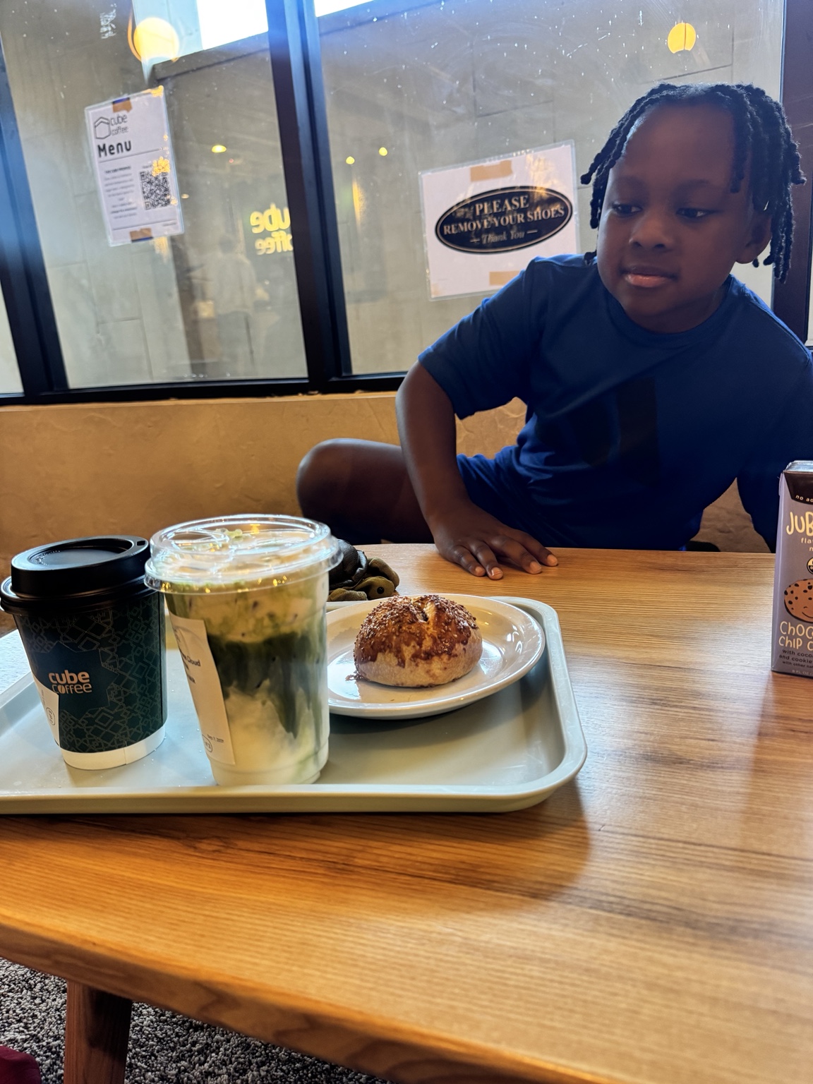 A child seated at Cube Coffee with Turkish food and drinks on the table.
