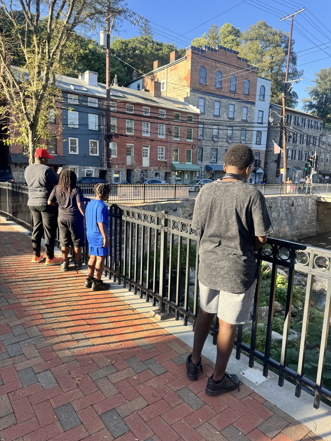 Denise Taylor's family standing by a railing in historic Ellicott City, looking out toward the creek and buildings.